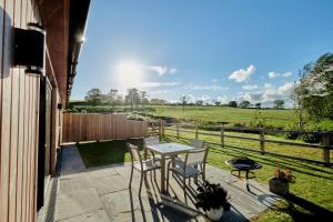 un patio con mesa, sillas y un campo en Ingleborough Lodge, en Settle