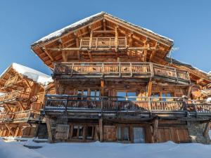 a large wooden house with a deck in the snow at Chalet aux pieds des pistes avec spa, sauna et parking - FR-1-645-43 in LʼHuez