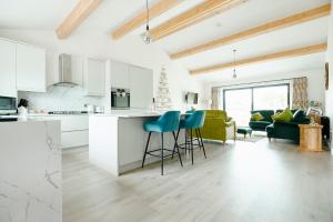 a kitchen and living room with white cabinets and blue stools at Whernside Lodge in Settle
