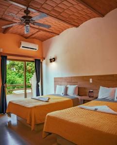 two beds in a room with a ceiling fan at Hotel & Suites Mar y Sol Las Palmas in Rincon de Guayabitos