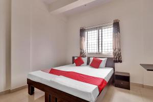 een slaapkamer met een bed met rode kussens en een raam bij OYO Flagship 81553 Green Residency in Bangalore