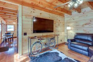 a living room with a tv and a bike on a wall at Forested Ellijay Cabin Rental with Private Hot Tub! in Ellijay