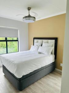 a bedroom with a large bed with white sheets and pillows at Feel at Home Mbombela Self Catering in Nelspruit