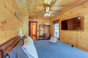 a log cabin bedroom with a large bed and a flat screen tv at Forested Ellijay Cabin Rental with Private Hot Tub! in Ellijay