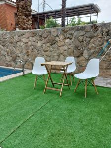 three chairs and a wooden table on grass next to a pool at Apartamento cercano a IFEMA, Aeropuerto, Clinica Universitaria Navarra y Civitas Metropolitano in Madrid