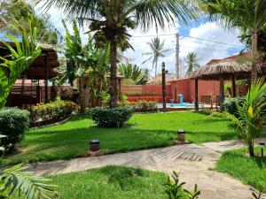 a garden with palm trees and a path at Pousada Casa Típica in São Miguel do Gostoso