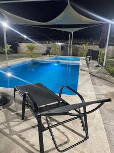 a black chair next to a swimming pool at night at Lomeli’s Home, Majahual Beach in La Libertad