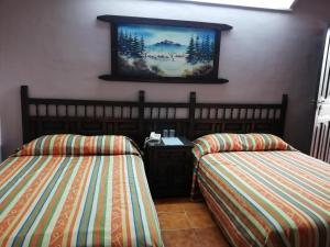 a room with two beds and a painting on the wall at Hotel Iberia in Córdoba