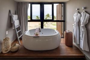 a bathroom with a large white tub and a window at BA'RA Hotel in João Pessoa