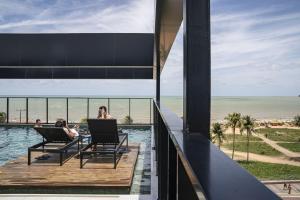 two people sitting in chairs on a deck near the beach at BA'RA Hotel in João Pessoa