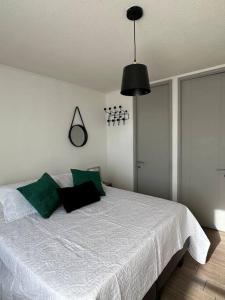 um quarto com uma grande cama branca com almofadas verdes em Depto full moderno Movistar Arena, Santiago de Chile em Santiago