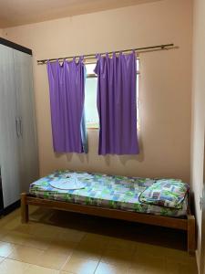 Cama en habitación con cortinas moradas en CASA NA SERRA, en São Roque de Minas