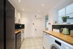 uma cozinha com armários brancos e um balcão de madeira em The Haze House - 4 Bed Townhouse em Bath