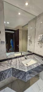 EWG Al Mashaer Hotel في مكة المكرمة: حمام مع حوض ومرآة كبيرة