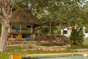 uma casa com uma cabana com cadeiras e uma mesa em Casa Rancho- Finca única en Yucatán em Hoctún