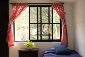 um quarto com uma janela com cortinas vermelhas e uma cama em Casa Rancho- Finca única en Yucatán em Hoctún