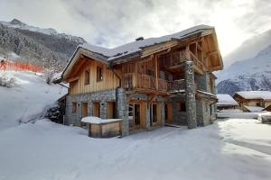 uma cabana de madeira na neve com neve em chalet ormelune au pied des pistes em Sainte-Foy-Tarentaise