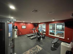 a gym with red walls and tread machines at Del-Mar Airport Inn & Suites in Shreveport