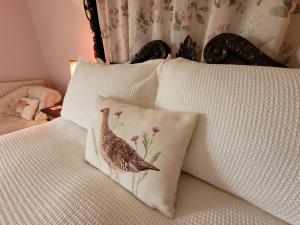 Una cama con almohadas con un pájaro. en Burton Grange Farmhouse Bed and Breakfast, en Boroughbridge