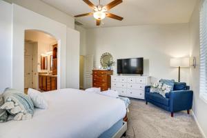 a bedroom with a bed and a tv and a blue chair at Goodyear Home with Pool, 6 Mi to Spring Training! in Goodyear