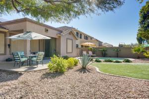 ein Haus mit einem Tisch, Stühlen und einem Sonnenschirm in der Unterkunft Goodyear Home with Pool, 6 Mi to Spring Training! in Goodyear