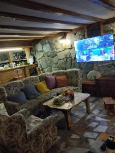 ein Wohnzimmer mit einem Sofa und einem TV in der Unterkunft Guest House Shuan in Chokhuldi