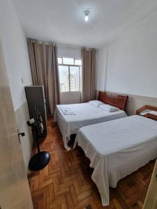 a hotel room with two beds and a window at Comodidade e Segurança no Centro in Belo Horizonte