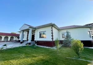 a house with a green lawn in front of it at Spacious and cozy villa in Bishkek