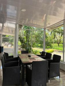 a dining room with a table and chairs and windows at Finca Nirvana. in Agua de Dios