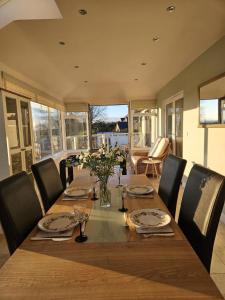 a dining room table with chairs and a wooden table with flowers at Meadow View in Haverfordwest