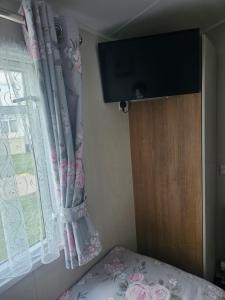 a bedroom with a bed and a window with a television at Private Caravan Camber Sands in Camber