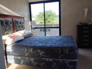 1 dormitorio con 1 cama y ventana grande en Alquiler Duplex Cosquin en Cosquín