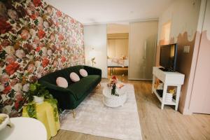 uma sala de estar com um sofá verde e uma televisão em The Garden Room at Waddington Flats em Victoria