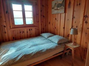 Cama en habitación de madera con ventana en Traditional chalet in the heart of nature, en Sarreyer