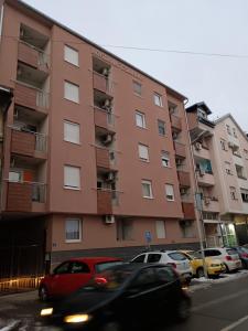 a tall building with cars parked in front of it at Alacaster G apartman FREE PARKING in Novi Sad