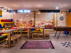 a room with a table and chairs and a wall with a mural at Gypsy Nest Hostel in Agra