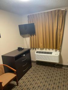 a room with a chair and a desk and a window at Economy Inn & Suites in Ashtabula