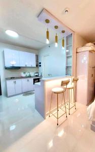a kitchen with white cabinets and a counter and stools at Condo Home in Puerto Princesa near PPS Airport in Puerto Princesa City