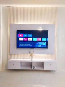 een flatscreen-tv zittend op een wit entertainment center bij Condo Home in Puerto Princesa near PPS Airport in Puerto Princesa City