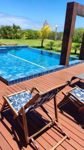 une paire de chaises assises sur une terrasse près d'une piscine dans l'établissement Casa PRAIA DO FORTE, à Praia do Forte