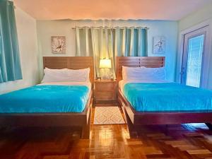 Blue House Miami في ميامي بيتش: سريرين في غرفة نوم بجدران زرقاء وأرضيات خشبية