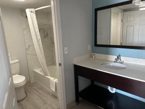 uma casa de banho com um lavatório, um WC e um espelho. em Siesta Inn em Fresno