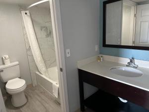 La salle de bains est pourvue de toilettes, d'un lavabo et d'une douche. dans l'établissement Siesta Inn, à Fresno