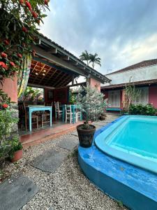 - une piscine en face d'une maison avec une table dans l'établissement Vila Luiza Ubatuba, à Ubatuba