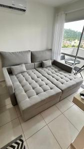 ein großes Sofa im Wohnzimmer mit Fenster in der Unterkunft Condomínio Vista Atlântico - Apartamento Novo - Próximo à Praia - Vista Mar - Área de Lazer in Itapema