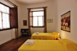 two yellow beds in a room with two windows at Casa dos Tios in Albufeira