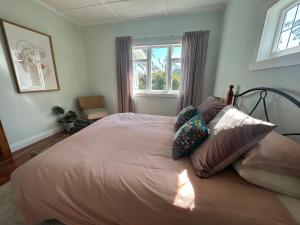 a bedroom with a bed with pillows and a window at Green Turtle Cottage in Pukenui