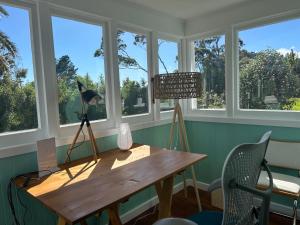 una mesa de madera en una habitación con ventanas en Green Turtle Cottage, en Pukenui