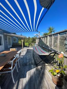 een terras met een hangmat en een tafel en stoelen bij Green Turtle Cottage in Pukenui