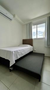 a small bedroom with a bed and a window at Condomínio Vista Atlântico - Apartamento Novo - Próximo à Praia - Vista Mar - Área de Lazer in Itapema